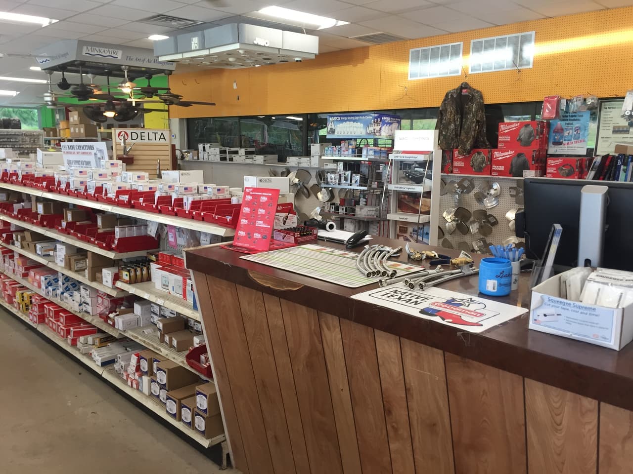 Wood-paneled service counter with shelves of electrical and plumbing parts and ceiling fans at Smith Supply in Stephenville, TX